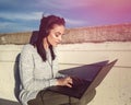 Young woman typing on laptop and listening music outdoor Royalty Free Stock Photo