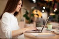 Young woman typing on laptop planning daily schedule and making to do list on coffee break in cafe. Royalty Free Stock Photo