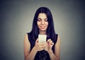 Young woman typing text message on smart phone having a pleasant conversation Royalty Free Stock Photo