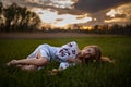 Young woman in Ukrainian national embroidered shirt lies on grass in meadow at sunset. Royalty Free Stock Photo