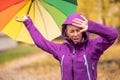 A young woman with an umbrella in a rain jacket wears a hood and protects her head from rain and strong wind during late autumn Royalty Free Stock Photo