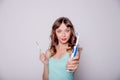 Young woman undecided whether to use the electric or traditional toothbrush, on white background.Oral hygiene