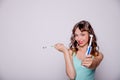 Young woman undecided whether to use the electric or traditional toothbrush, on white background.Oral hygiene