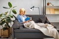 Young woman under a blanket reading book on couch Royalty Free Stock Photo