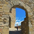 Young woman under Old stone arch gate and narrow street in the medieval village of Anghiari near city of Arezzo in Tuscany, Italy