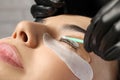 Young woman undergoing eyelash lamination, closeup. Professional service