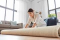 Young woman unfolding carpet at home Royalty Free Stock Photo