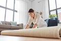 Young woman unfolding carpet at home