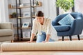 Young woman unfolding carpet at home