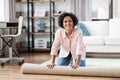 young woman unfolding carpet at home Royalty Free Stock Photo