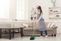 Young woman sweeping house with broom and scoop