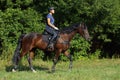 Young woman in uniform and helmet riding horse