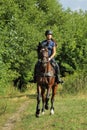 Young woman in uniform and helmet riding horse