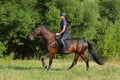 Young woman in uniform and helmet riding horse