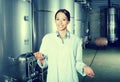 Young woman in uniform standing in winery fermentation