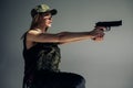 Young woman in uniform stands and aims with handgun in her hand