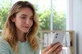 Young woman unlocking smartphone with facial scanner indoors. Biometric verification