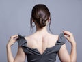 Young woman with unzipped zipper on the dress. Bunette female rear view with hair knot and earrings in the ears Royalty Free Stock Photo