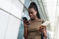 Young african woman use on cellphone and holding passport in airport terminal while waiting for flight Royalty Free Stock Photo