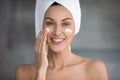 Young woman use revitalizing facial cream in bathroom Royalty Free Stock Photo