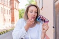 Young woman uses her phone as a mirror while standing in a city park