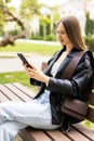 Young woman uses smartphone sitting on bench in the Park Royalty Free Stock Photo