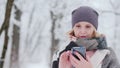 Young woman uses smartphone in snow park