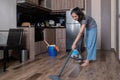 Young woman uses a vacuum cleaner to clean the kitchen floor. Cleaning the house during the holidays Royalty Free Stock Photo