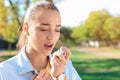 Young woman using asthma inhaler outdoors Royalty Free Stock Photo