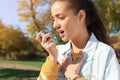 Young woman using asthma inhaler outdoors Royalty Free Stock Photo