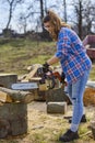 Young Woman using chainsaw to cut a log