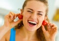 Young woman using cherry tomato as earrings Royalty Free Stock Photo