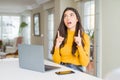 Young woman using computer laptop amazed and surprised looking up and pointing with fingers and raised arms Royalty Free Stock Photo