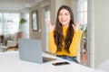 Young woman using computer laptop celebrating mad and crazy for success with arms raised and closed eyes screaming excited Royalty Free Stock Photo