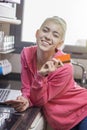 Happy young woman with laptop using credit card and phone in kit Royalty Free Stock Photo