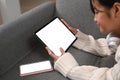 Young woman using digital tablet while lying on sofa in living room. Royalty Free Stock Photo