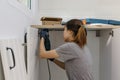 Young woman using electric screwdriver to installation