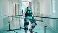 Young woman is using exosuit for walking in the hospital