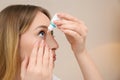 Young woman using eye drops on beige Royalty Free Stock Photo