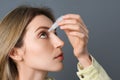 Young woman using eye drops on dark grey background, closeup Royalty Free Stock Photo