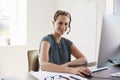 Young woman using headset and computer smiling to camera Royalty Free Stock Photo