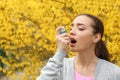 Young woman using inhaler near blooming tree. Allergy concept Royalty Free Stock Photo