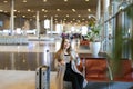 Young woman using internet by tablet in airport hall near valise and showing thumbs up. Royalty Free Stock Photo