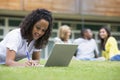 Young woman using laptop on campus lawn Royalty Free Stock Photo