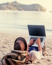 Young woman using laptop computer on a beach. Freelance work con Royalty Free Stock Photo