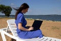 Young woman using laptop computer on a beach. Freelance work concept Royalty Free Stock Photo