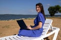 Young woman using laptop computer on a beach. Freelance work concept Royalty Free Stock Photo