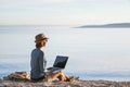 Young woman using laptop computer on a beach. Freelancer working by the sea, vacations, business, people, Royalty Free Stock Photo