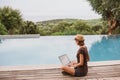 Young woman using laptop computer near swimming pool in hotel Royalty Free Stock Photo