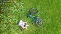 Young woman using laptop computer in park, student girl sitting on grass with bicycle and laptop, aerial drone view Royalty Free Stock Photo